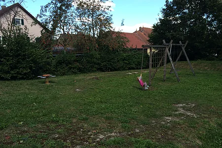 Mädchen sitzt auf Schaukel mit runder Sitzfläche.