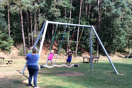 Mutter mit Kindern besucht die moderne Stehschaukel.