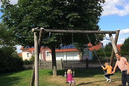 Kleine Kinder schaukeln mit Papa.